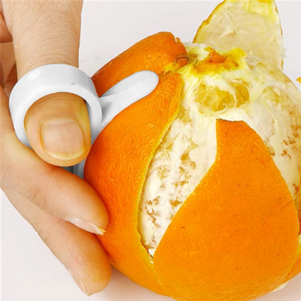 Hand using a ring-shaped tool to easily peel an orange skin.